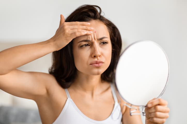 Upset millennial woman looking at mirror